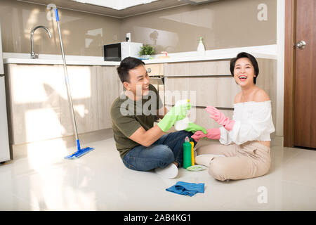 Young happy couple is having rest after doing cleaning at home. Stock Photo