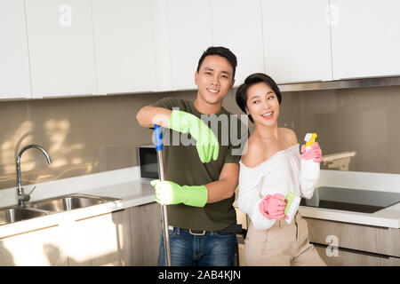 Young happy Asian couple is having fun while doing cleaning at home. Stock Photo