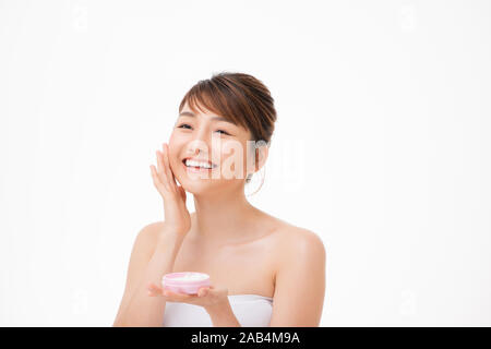 Beauty concept. Asian girl is applying cream on her face. Stock Photo