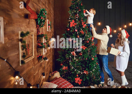 Loving family decorating Christmas tree together Stock Photo