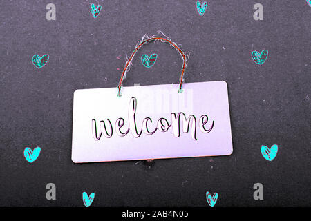 Welcome wording on black notice board  with red hearts around Stock Photo