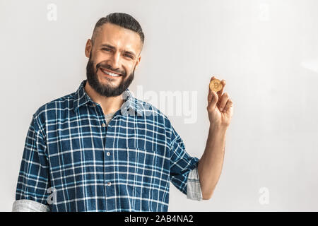 Mature bearded man holding gold bitcoin in hand Stock Photo