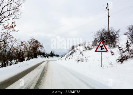 Snow winter road and Z warning road sign in Serbia Stock Photo