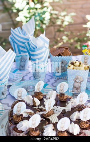 Festive table setting for children. Decoration for children's party. Teddy bear style serving. Cake, parcels, cookies, cups, plates and napkins are wh Stock Photo