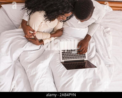 Top view of black couple using laptop in bed Stock Photo