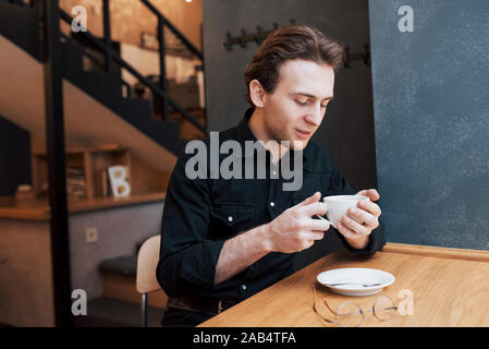 Handsome bearded man in checked shirt holding fork eating in cafe and smiling Stock Photo