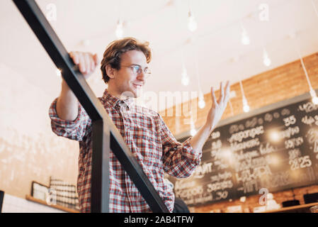 Thoughtful young man is sitting in confectionery shop. She is drinking coffee while waiting for someone Stock Photo