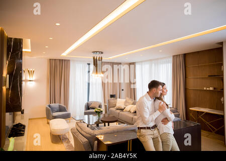 Young couple embracing standing in living room of a contemporary apartment Stock Photo