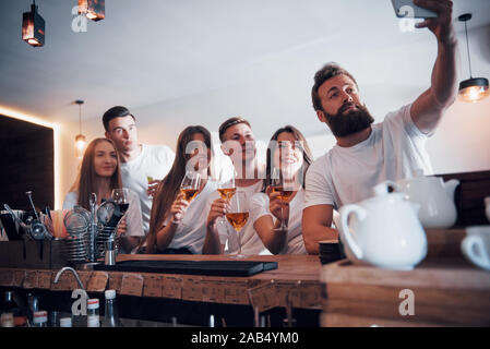 Leisure and communication concept. Group of happy smiling friends enjoying drinks and talking at bar or pub