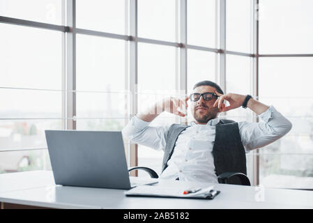Worker is a young man with a laptop in the office Stock Photo
