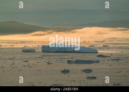 Stranded icebergs in the fog at the mouth of the Icefjord near Ilulissat. Nature and landscapes of Greenland. Travel on the vessel among ices Stock Photo
