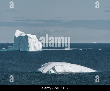 Huge floating iceberg in deep blue ocean water. Greenland and Antarctica, near Ilulissat. Global warming concept. Blue Sky and ice fjord. Stock Photo