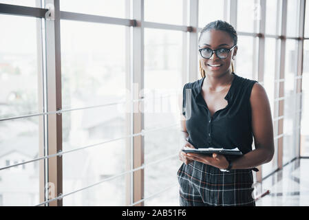 A thoughtful African American business woman wearing glasses holding documents Stock Photo