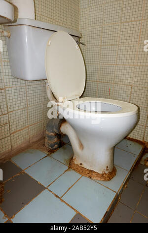 Defective old toilet and broken tiles Stock Photo