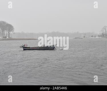 Old fishing workboat moored in harbor during a winter storm. Stock Photo