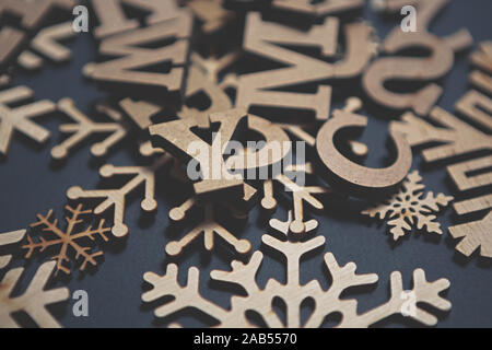 Winter holidays handmade crafts in close up.Wooden snowflakes and letters on blue background.Holiday decor objects in macro,edited with fading film fi Stock Photo