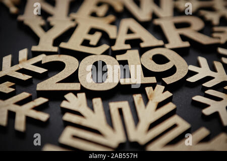 Happy New Year 2019 wallpaper.Black background with wooden letters and figures shot in close up macro style.Rustic style backdrop for winter holidays Stock Photo