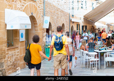 ALCUDIA, SPAIN - July 8, 2019: Restaurant tables on street with tourists in seaside Alcudia old town, Mallorca island, Spain Stock Photo