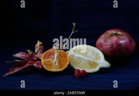 tangerine and lemon open-face with seed and a pomegranate on a black and dark blu background Stock Photo