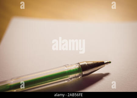 Green gel pen on a white notebook paper, an accessory for creativity on the table. Stock Photo
