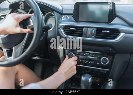 Close-up, girl adjusts air conditioning switch passenger compartment, turning on and off volume mode for seat heating and climate passenger Stock Photo
