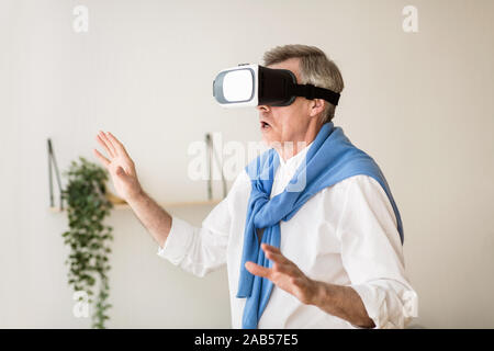 Excited senior man using VR glasses, having fun Stock Photo