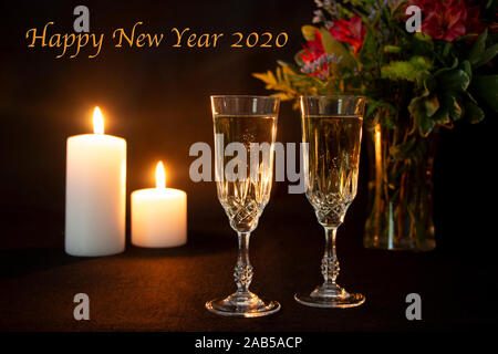 Happy New Year 2020 Text with Candles and  Two Champagne Flutes Stock Photo
