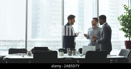 Businessmen talking by conference table in office, free space Stock Photo