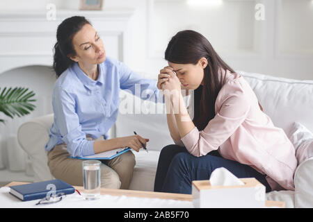 Therapist comforting her depressed crying woman patient Stock Photo