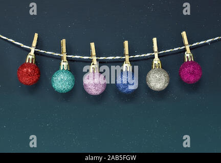 Multicoloured glittering Christmas baubles hanging on a string on a dark background, with copy space Stock Photo