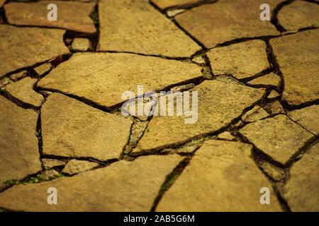 Road surface made of natural wild stones, yellow tone. Stock Photo