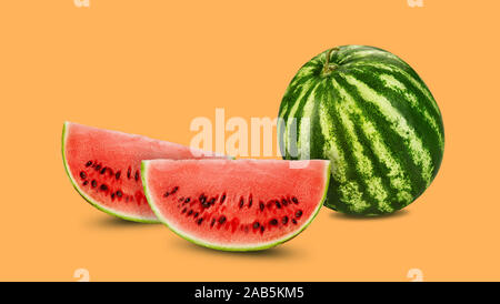 Green, striped watermelon, orange background with copy space for text, image. Cross-section. Berry with pink flesh, black seeds. Side view. Close-up. Stock Photo