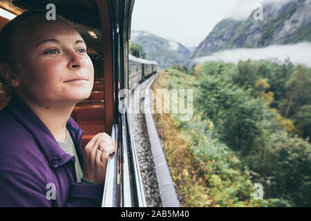 Woman enjoying a ride and looking out the window on Flamsbana mountain railway in Flam, Norway. Stock Photo