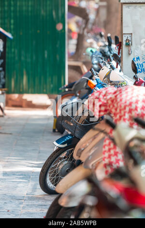 Rows of colorful scooters, mopeds and bikes parked in a row on a quiet street in Hanoi, Vietnam, Asia Stock Photo