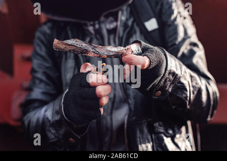 Drug addict smoking opium on tin foil, aka chasing the dragon, close up of hands with selective focus Stock Photo