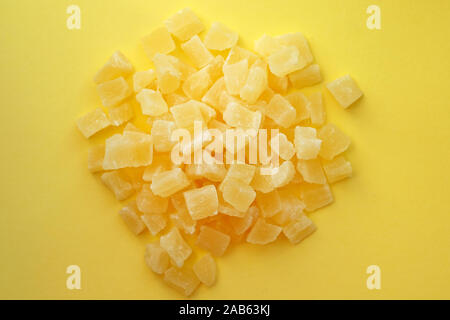 Pieces of dried pineapple on a yellow background. Candied fruits top view. Stock Photo