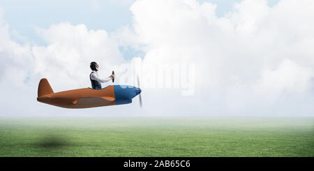 Man in airplane flying low above green meadow Stock Photo