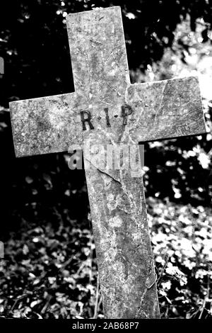 A wonky stone cross in a cemetery with R.I.P sign engraved Stock Photo