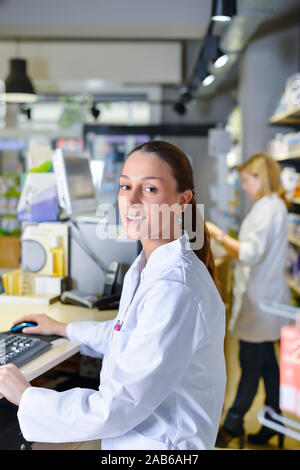 Young female pharmacist working on computer Stock Photo