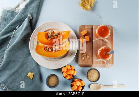 Organic pumpkin jam in the glass jars on the gray background decorated with pumpkins. Autumn recipes, dishes from a pumpkin.  Flat lay, horizontal. Stock Photo