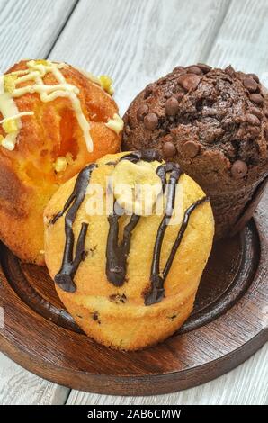 Sweet and tasty snack. Three different colorful cupcakes on a wooden background. Stock Photo