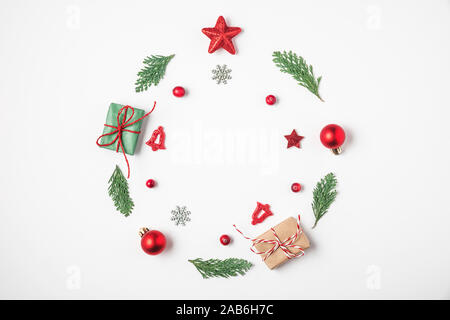 Christmas wreath made of fir tree branches, red decorations, gift boxes, pine cones on white background. Christmas, winter, new year concept. Flat lay Stock Photo