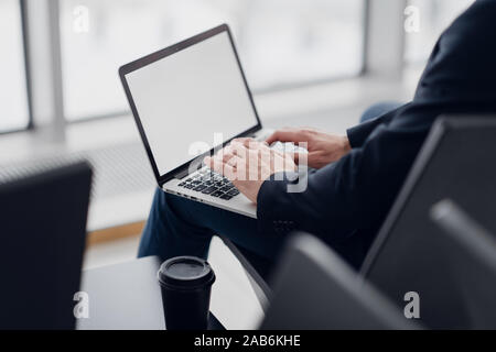 Businessman using laptop with blank screen at public place Stock Photo