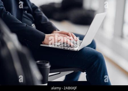 Close up of young freelance business man hands typing on a laptop keyboard while working remotely. Stock Photo