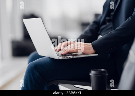 Close up of young freelance business man hands typing on a laptop keyboard while working remotely. Stock Photo