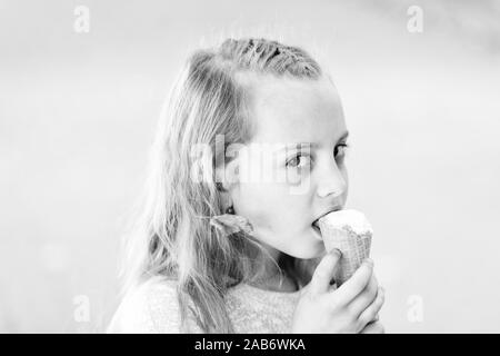 Lick frozen yoghurt. Girl sweet tooth eat ice cream. Kid with ice cream cone in hand. Child white ice cream in waffle cone. Summer treats concept. Happy childhood. Buy ice cream street food. Stock Photo