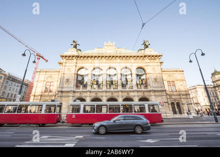 VIENNA, AUSTRIA - NOVEMBER 6, 2019: Trams passing by in speed and cars driving in front of the Vienna Opera House, or wiener staatsoper. It is the mai Stock Photo