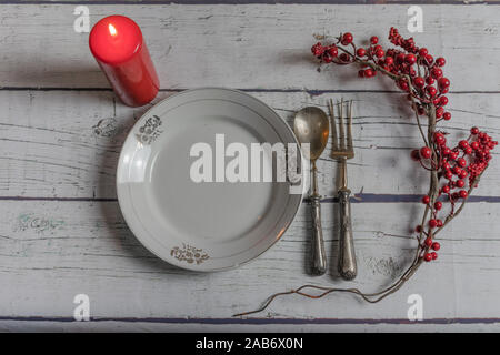Christmas table with antique silver cutlery, red candle on a white wooden background Stock Photo