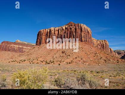 A natural red rock fortress reaches toward the brilliant blue sky in Canyonlands National Park. Stock Photo