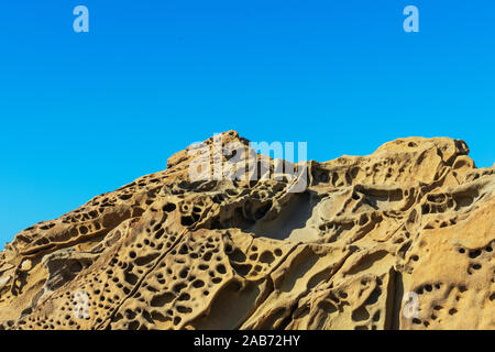 Tafoni formation, uniquely textured sandstone, cave like features and honeycomb like structures created in rock through a weathering process. Blue sky Stock Photo